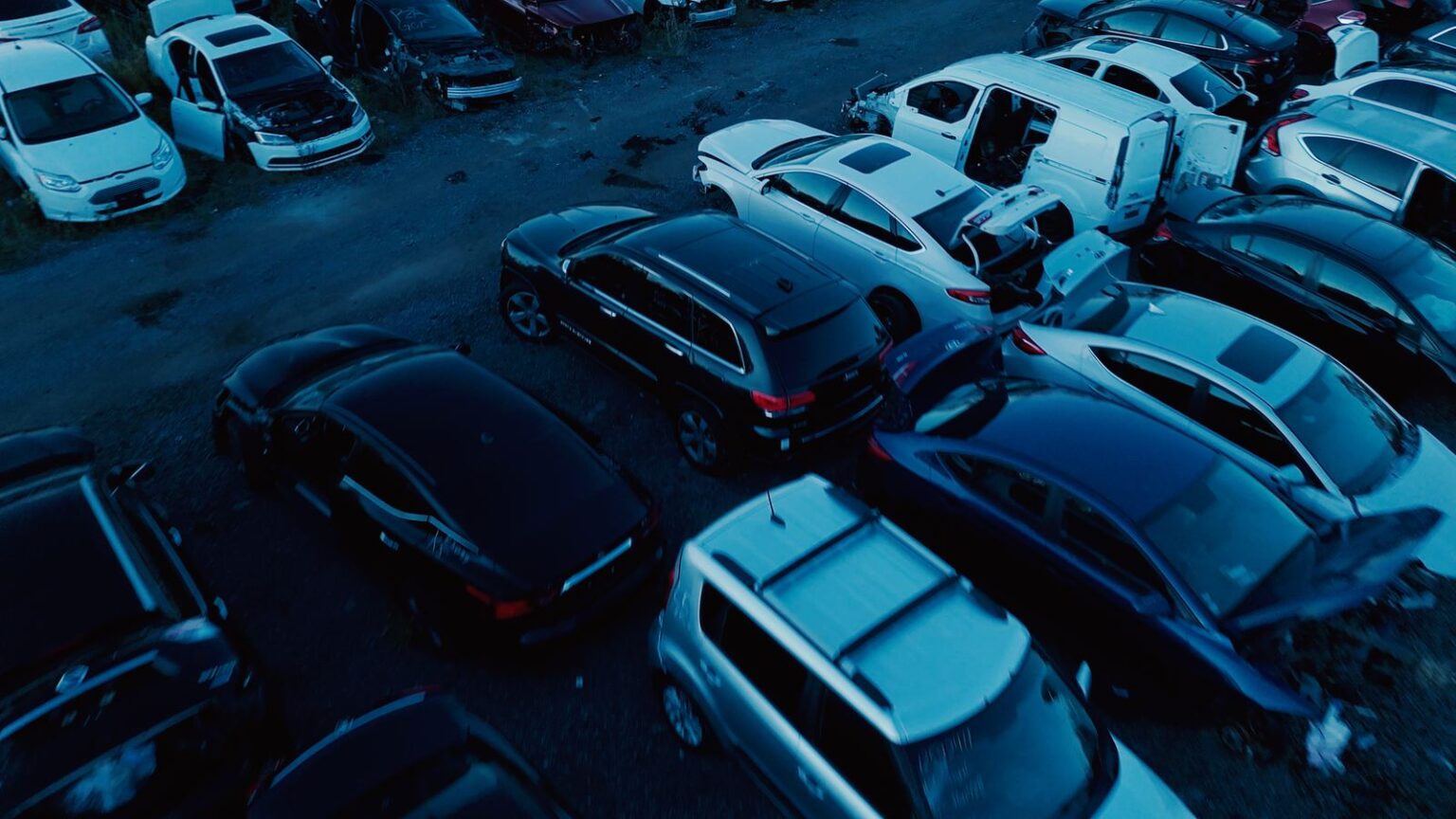 Scrapped cars and SUVs in the GTA Auto Recycling yard, doors and hatches open where parts have been pulled